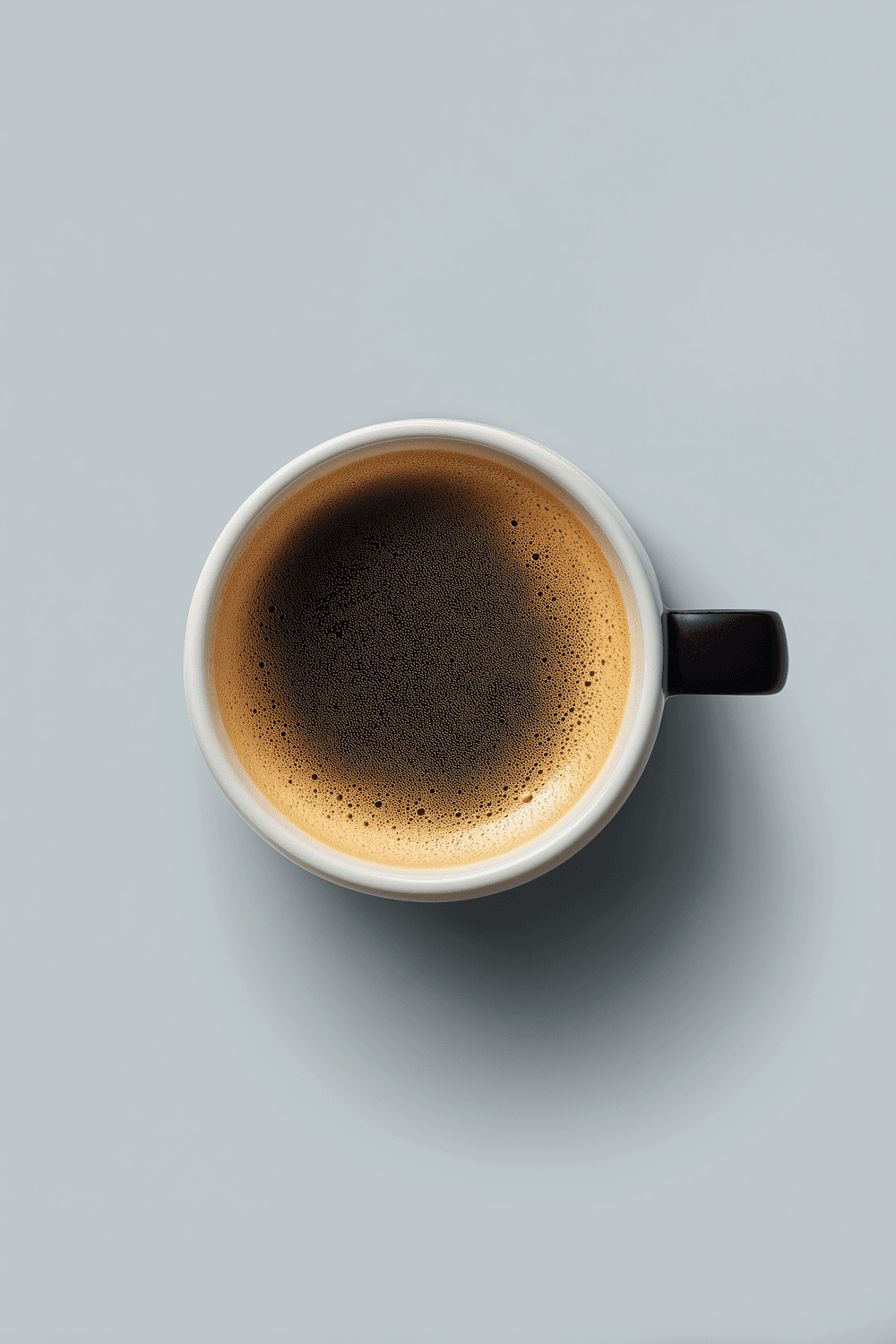 Top-down view of an espresso in a white cup on a pale grey surface